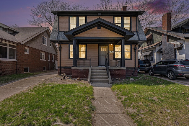 view of front of home featuring a yard, a porch, and a chimney
