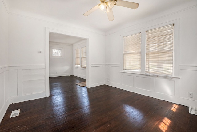 empty room featuring a decorative wall, a wainscoted wall, and a ceiling fan