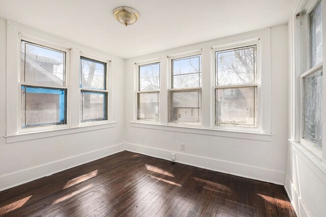 empty room with baseboards and dark wood-style flooring