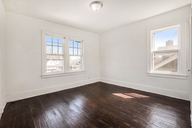 unfurnished room with baseboards and dark wood-style floors
