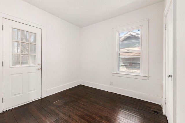 unfurnished room featuring baseboards and dark wood-style floors