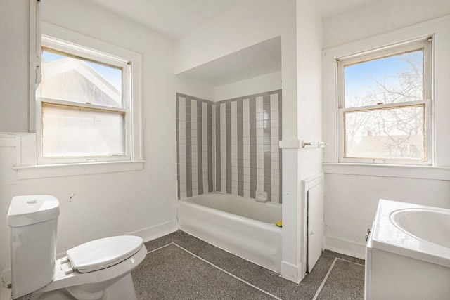 bathroom with toilet, vanity, tub / shower combination, and baseboards
