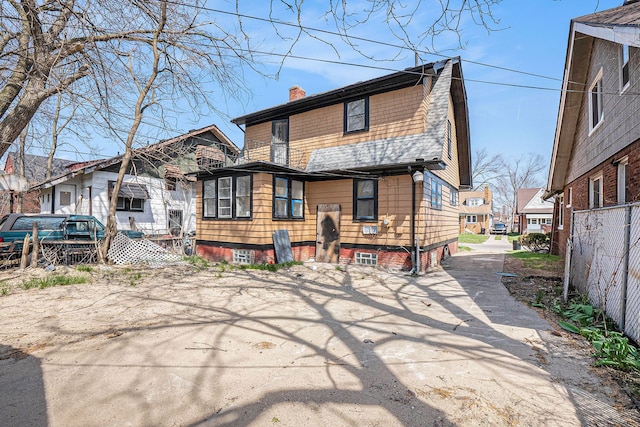 back of house featuring fence, a shingled roof, and a chimney
