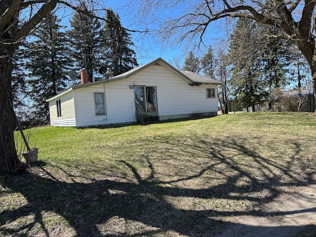 rear view of house featuring a chimney and a lawn