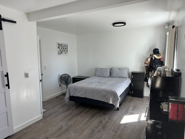 bedroom featuring baseboards, a barn door, and wood finished floors
