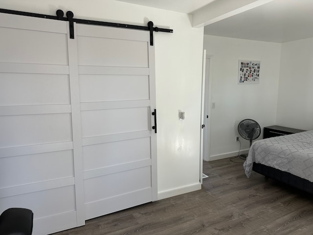 bedroom with dark wood-style flooring, baseboards, and a barn door