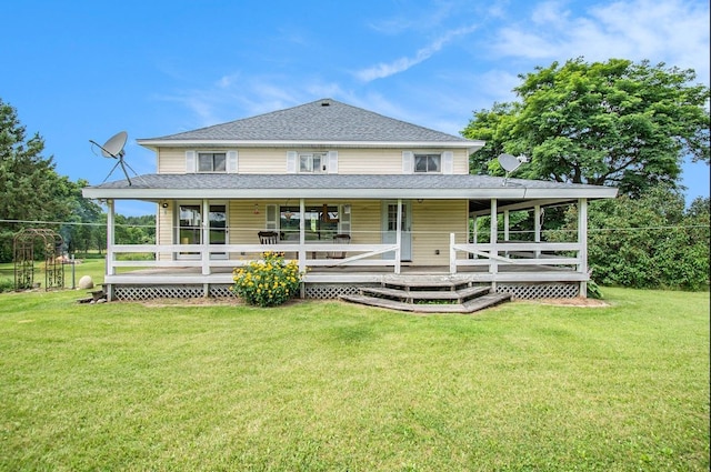 back of property with a porch, roof with shingles, and a lawn