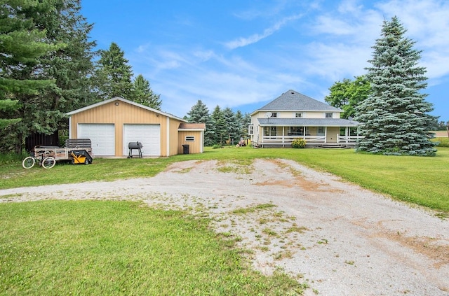 view of front of house with an outbuilding, a front lawn, covered porch, and a garage