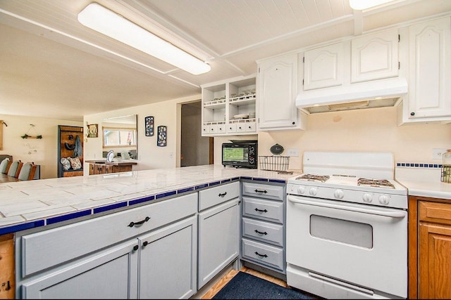 kitchen featuring white gas range oven, a peninsula, open shelves, white cabinets, and under cabinet range hood