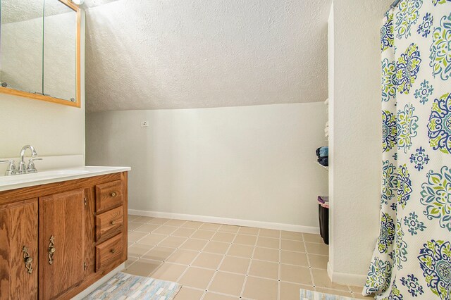 bathroom with a textured ceiling, vanity, and baseboards