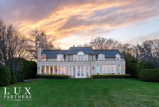back of house with a chimney, a high end roof, a yard, and french doors