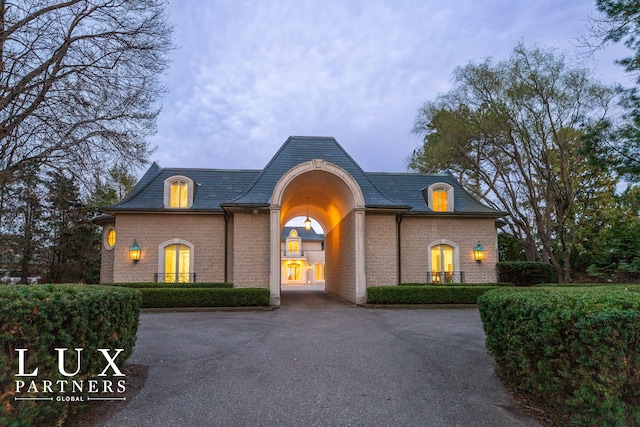 view of front of property featuring a high end roof, brick siding, and driveway