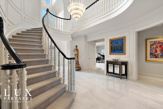 stairs with baseboards, a decorative wall, a high ceiling, and an inviting chandelier