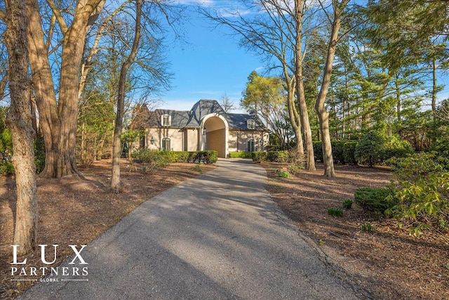 tudor home with aphalt driveway and stucco siding