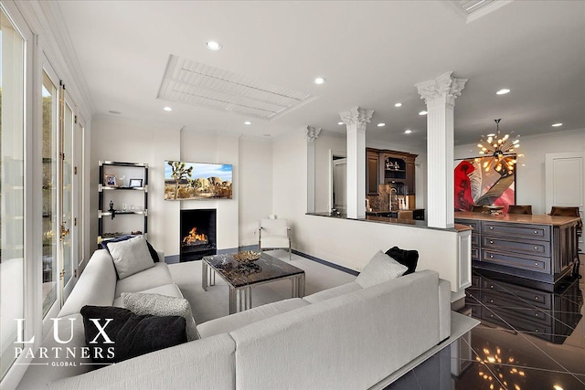 living area featuring recessed lighting, a warm lit fireplace, ornamental molding, baseboards, and decorative columns