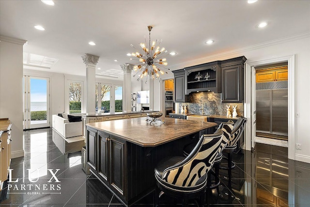 kitchen with a sink, granite finish floor, recessed lighting, decorative backsplash, and a kitchen island