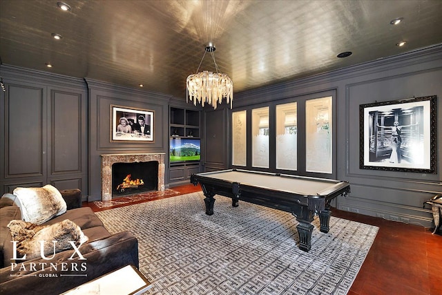 playroom with a decorative wall, ornamental molding, built in shelves, and a fireplace