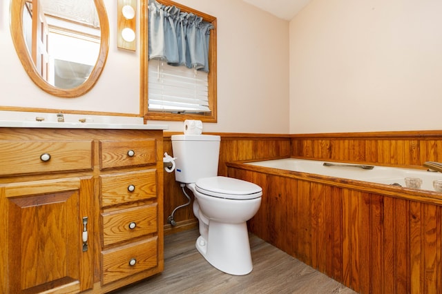 full bathroom featuring vanity, a garden tub, toilet, and wood finished floors
