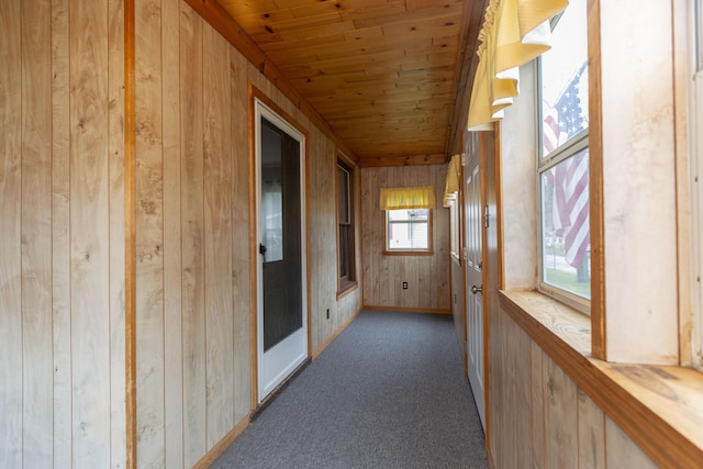 corridor featuring wooden walls, carpet, and wood ceiling