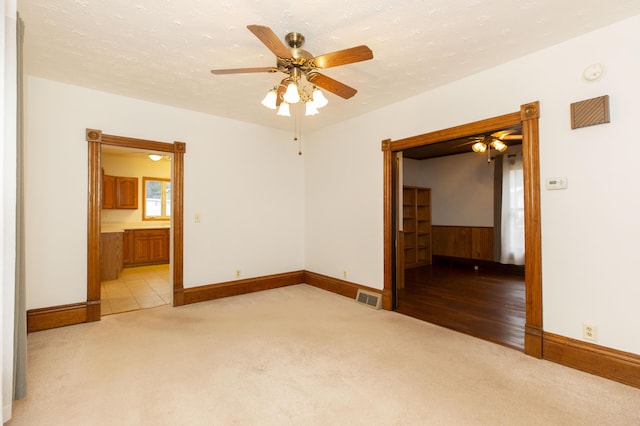 spare room with visible vents, light colored carpet, and baseboards