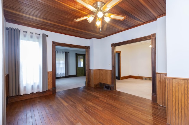 spare room with visible vents, wooden ceiling, ceiling fan, wainscoting, and wood-type flooring