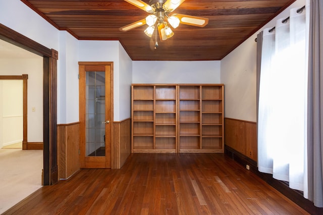 additional living space featuring dark wood finished floors, wooden ceiling, wood walls, and wainscoting