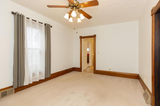 spare room featuring light colored carpet, baseboards, and visible vents