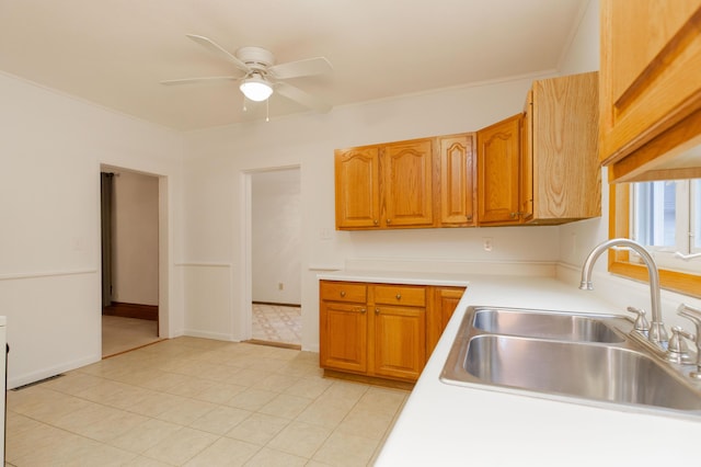 kitchen with brown cabinetry, light countertops, a sink, and a ceiling fan