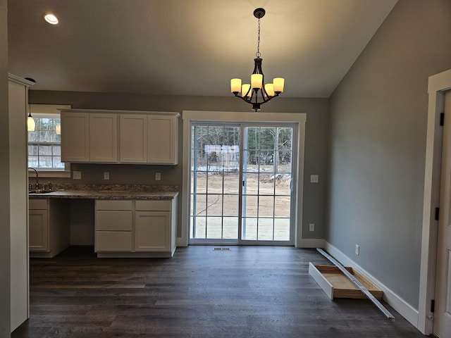 unfurnished dining area with baseboards, an inviting chandelier, a sink, recessed lighting, and dark wood-type flooring
