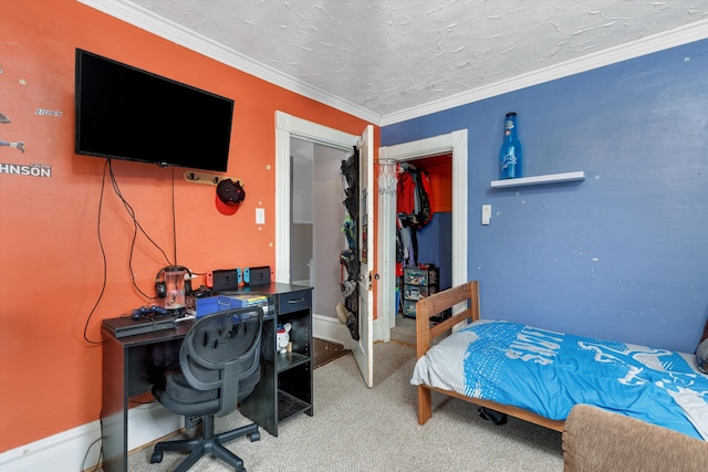 carpeted bedroom with a closet, crown molding, and baseboards