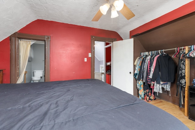 bedroom with connected bathroom, ceiling fan, vaulted ceiling, and wood finished floors