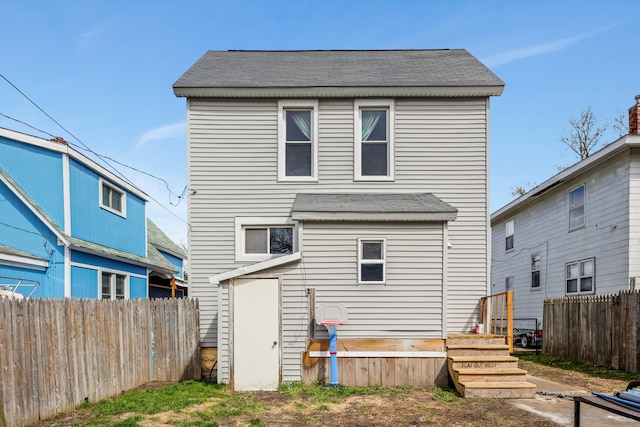 back of property with fence and roof with shingles