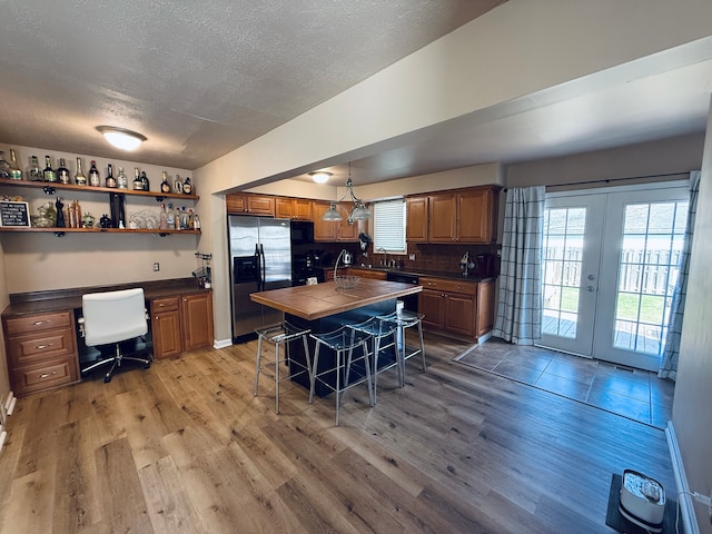 kitchen with tile countertops, stainless steel fridge with ice dispenser, a textured ceiling, and light wood finished floors