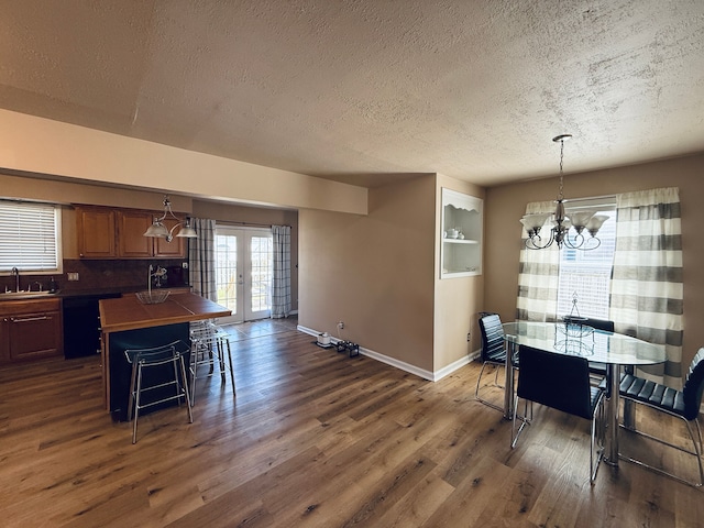 dining area with a notable chandelier, french doors, baseboards, a textured ceiling, and dark wood-style flooring