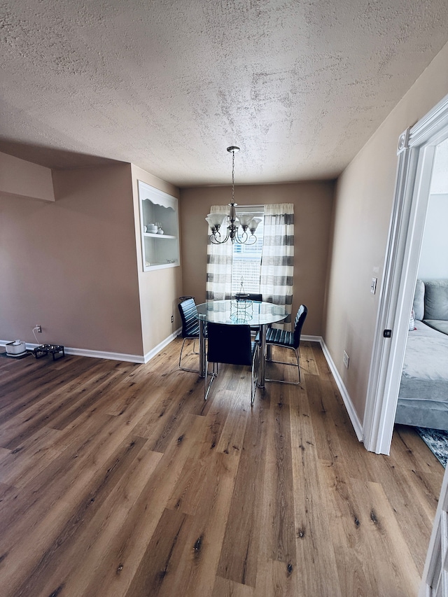 dining area featuring an inviting chandelier, wood finished floors, and a textured ceiling
