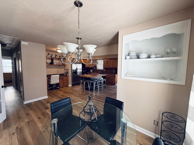 dining area featuring a textured ceiling, baseboards, dark wood-style flooring, and an inviting chandelier