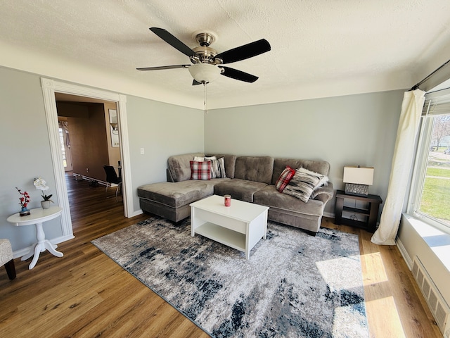 living area with visible vents, a ceiling fan, wood finished floors, and a healthy amount of sunlight