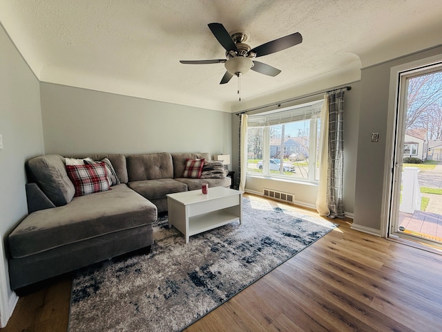 living room featuring a textured ceiling, wood finished floors, and visible vents