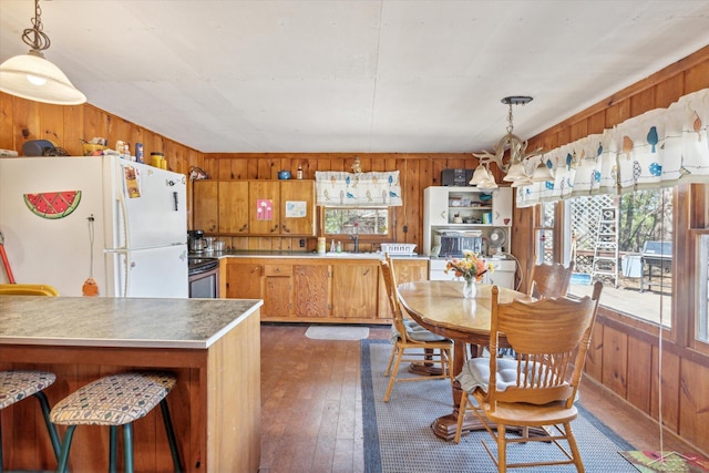 kitchen featuring plenty of natural light, wooden walls, freestanding refrigerator, and stainless steel counters