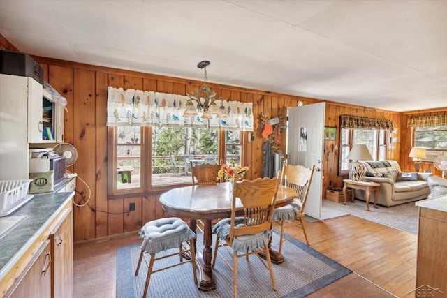 dining area with wood walls, light wood finished floors, and a chandelier