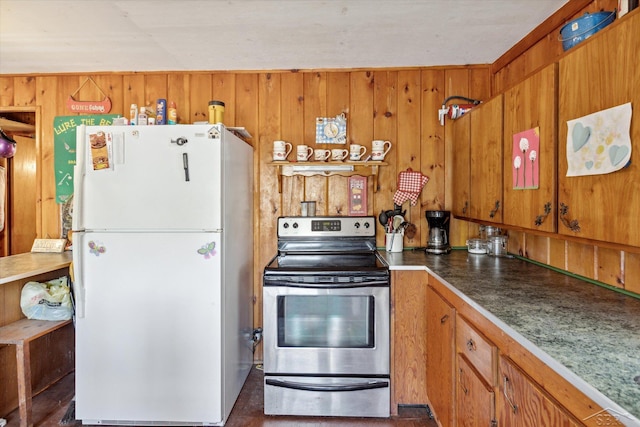 kitchen featuring stainless steel range with electric stovetop, wooden walls, brown cabinets, and freestanding refrigerator