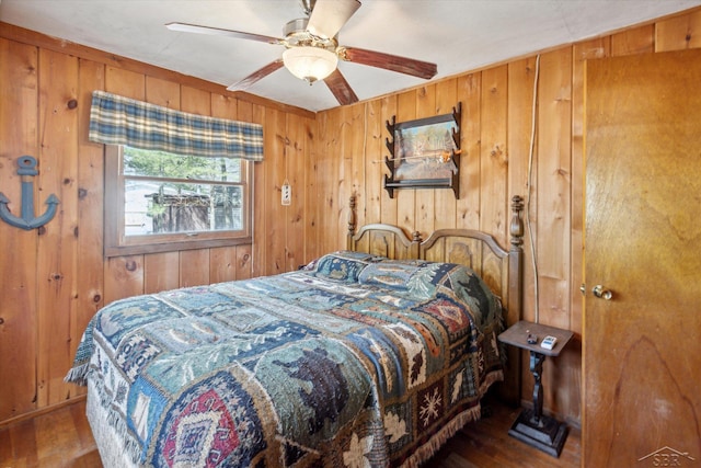 bedroom with wood finished floors, wood walls, and a ceiling fan