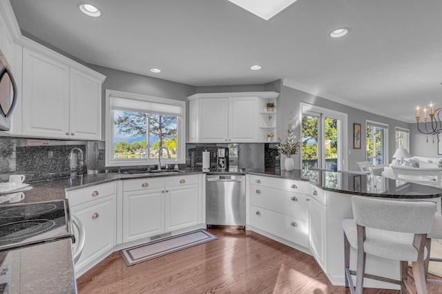 kitchen with a peninsula, dishwasher, a sink, and a wealth of natural light