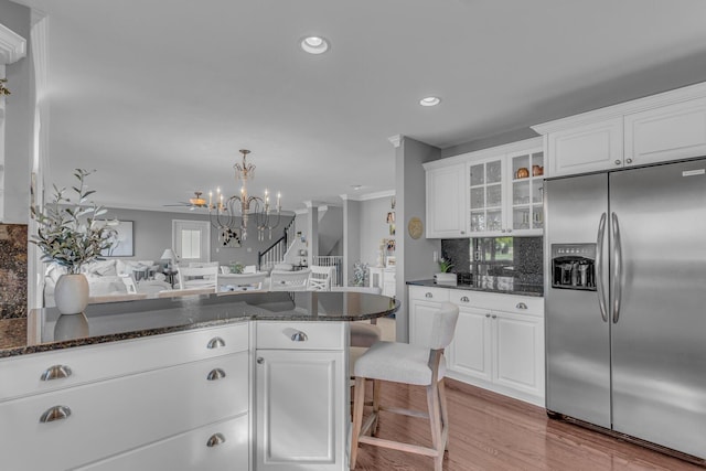 kitchen with stainless steel fridge with ice dispenser, glass insert cabinets, white cabinets, and a notable chandelier
