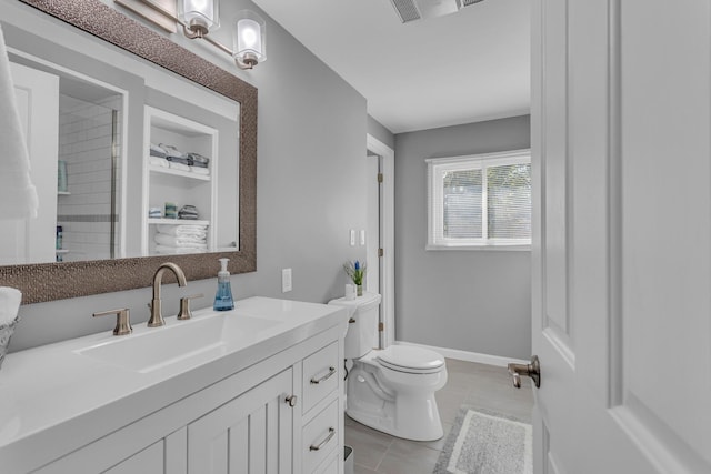 bathroom with a tile shower, vanity, tile patterned flooring, visible vents, and toilet