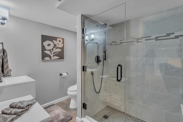 full bath featuring toilet, a stall shower, vanity, and baseboards