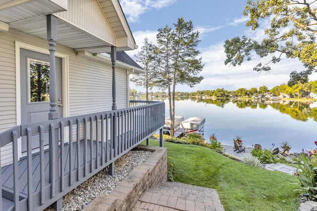 view of side of property with a water view, a lawn, and roof with shingles