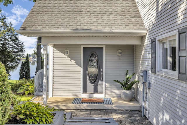 doorway to property featuring a shingled roof and covered porch