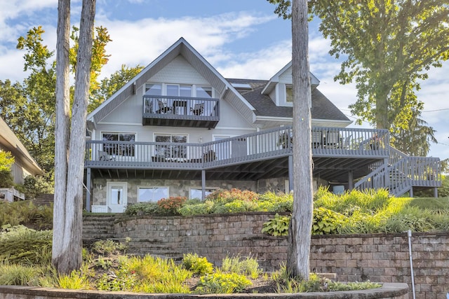 rear view of property with a balcony and a shingled roof