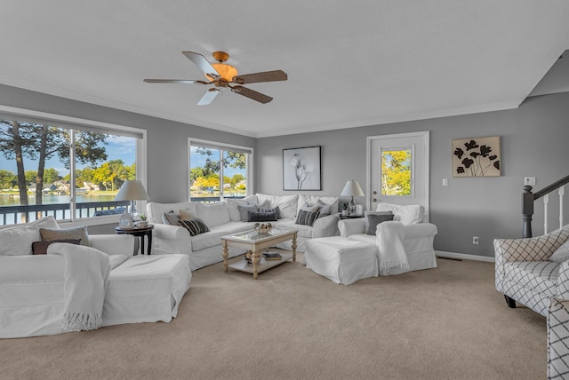 carpeted living room with a water view, ornamental molding, ceiling fan, and baseboards